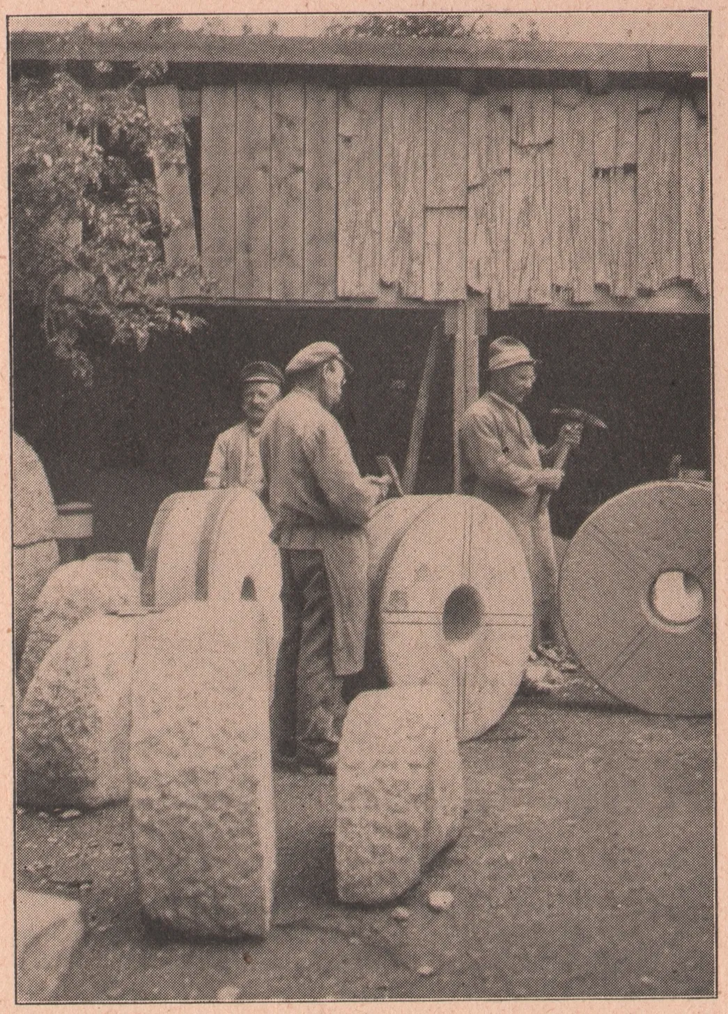 A vintage sepia photograph of craftsmen dressing a millstone by hand in an old workshop